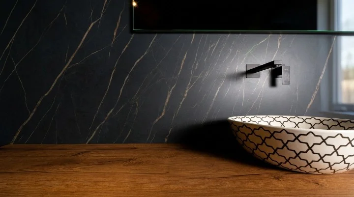 Veined black marble wall with matt black wall-mounted tap, wooden worktop and oriental-pattern basin — Osmosis Home Tangier bathroom